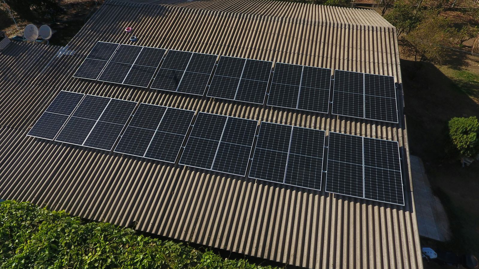 Aerial view of a Geonergy rooftop solar array: twenty black panels mounted in two rows across a corrugated roof.